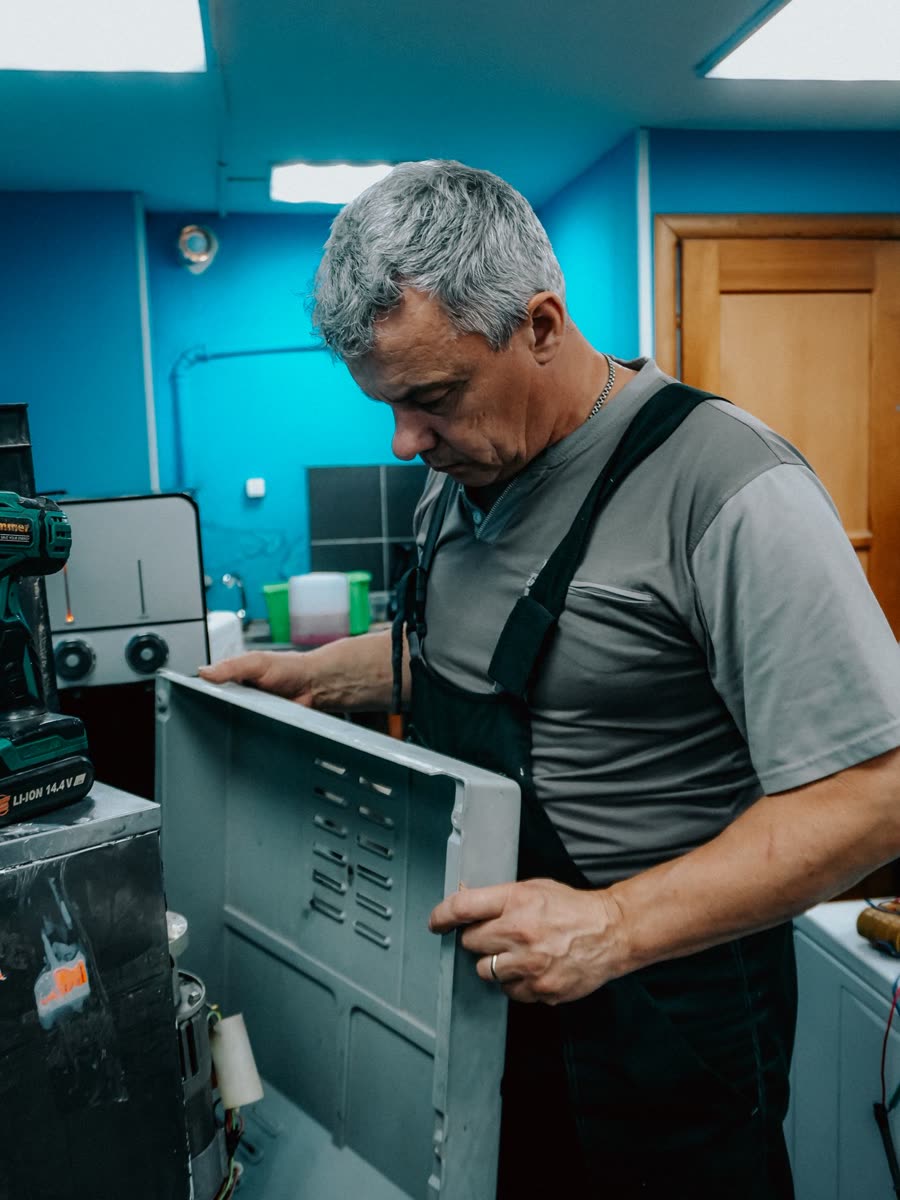 MERA ENGINEER technician opening the rear panel of a commercial refrigerator for repair